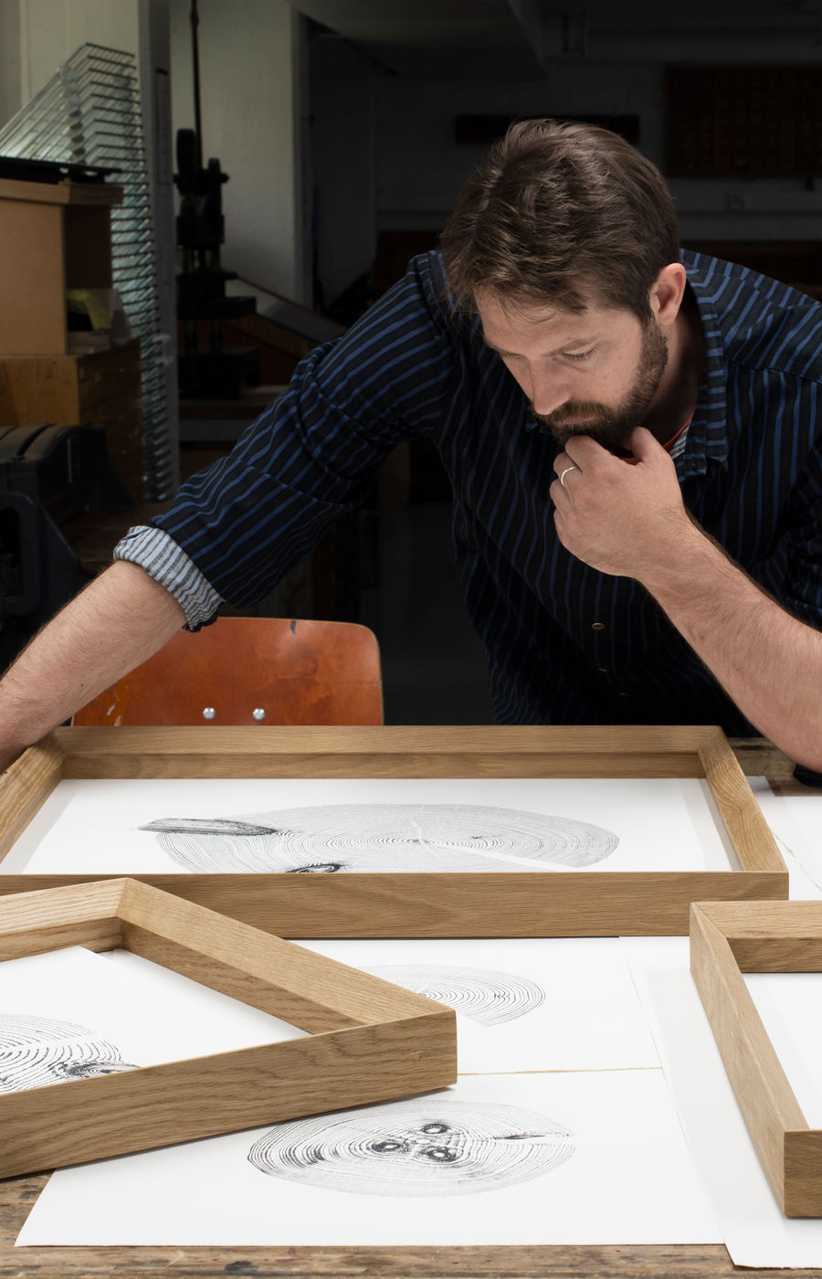 Josh Krute, artist behind The Trees of Pikku-Finlandia, pictured in his studio with the wood prints and wooden frames.