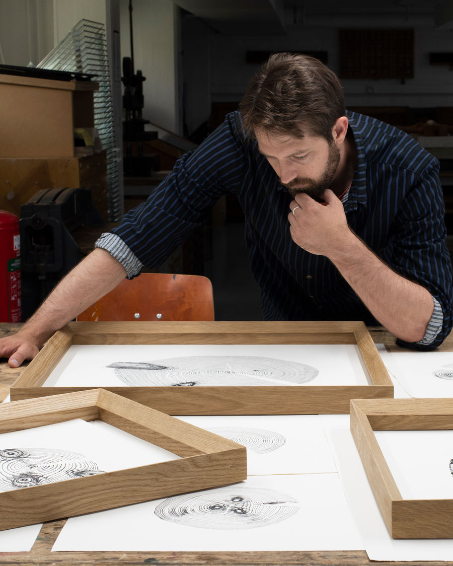 Josh Krute, artist behind The Trees of Pikku-Finlandia, pictured in his studio with the wood prints and wooden frames.